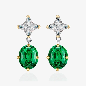 Close-up of elegant emerald-style oval studs with gold claw settings and star accents