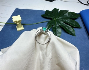 Détail macro d'une bague en argent sertie d'une pierre verte ovale et de zircons