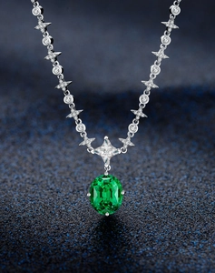 Macro view of emerald pendant necklace with star-shaped silver link chain detail