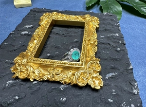 Macro shot of 8mm oval green gemstone ring with pavé diamonds in vintage frame