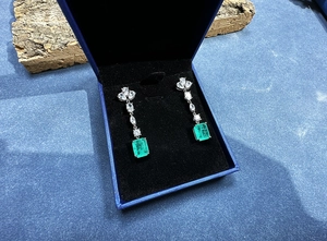 Detailed view of 8x10mm emerald cut drop earrings presented in a blue jewelry gift box