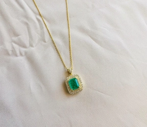 Macro detail of rectangle emerald pendant necklace with double halo gold setting