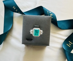 Macro detail of emerald-cut green gemstone ring set in silver within a jewelry box