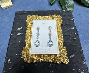 Detail of silver S925 drop earrings with pear-cut blue topaz on a vintage display