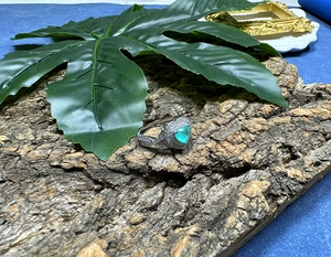 Macro detail of heart-shaped Paraiba gem ring with pave-set accents on bark
