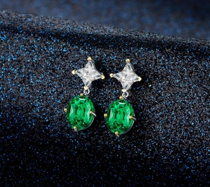 Close-up of oval emerald green zircon earrings with silver and gold-tone claw settings