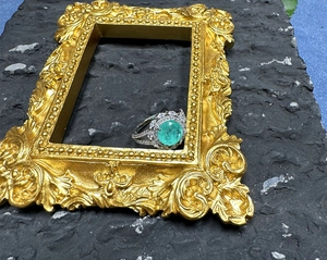 Close-up of a 925 silver halo ring with a green gemstone on a vintage gold frame