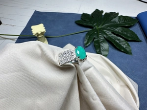 Détail d'une bague avec grosse pierre ovale verte et diamants pavés sur anneau en argent