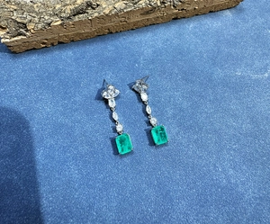 Macro shot of 8x10mm emerald cut green gemstones and zircon stones on silver earrings