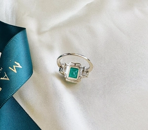 Macro detail of emerald-cut green gemstone ring set in silver with side stone accents