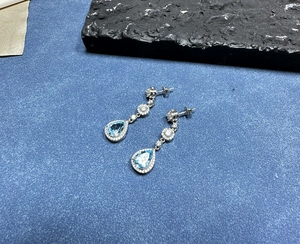 Close-up of teardrop blue topaz sterling silver drop earrings with micro-pave detailing