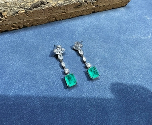 Detail view of 8x10mm emerald-cut green gemstone earrings with cluster zircons
