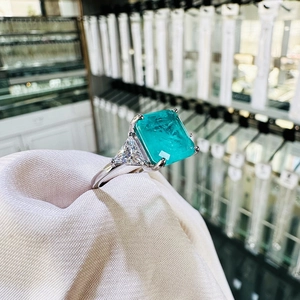 Three-stone emerald cut blue gemstone ring in 925 silver setting with side stones