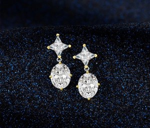 Detail of silver drop earrings with star and oval cut clear gemstones on blue fabric