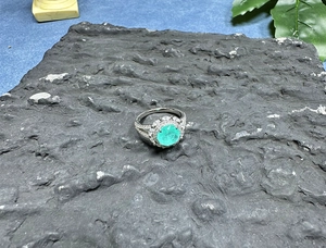 Detailed view of an 8mm oval Paraiba blue gemstone ring set on a natural rock surface
