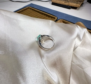 Detail of 8mm round light green gemstone ring set in silver with pavé zircon accents