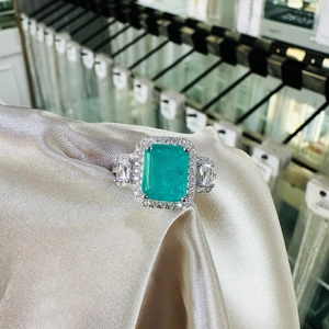 Silver ring featuring a large emerald-cut green gemstone with tapered baguette accents