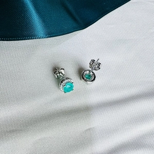 Elegant 925 silver halo stud earrings with 5mm round emerald green stones on white silk