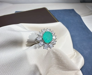 Macro detail of oval Paraiba gem ring with double halo diamond setting on silk