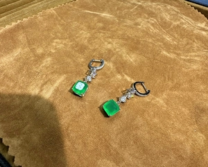 Detail of square emerald cut green gem earrings with silver drop and zircon accents