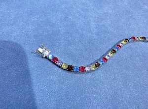 Dettaglio macro di un bracciale tennis colorato con pietre multicolori e castone a 4 griffe