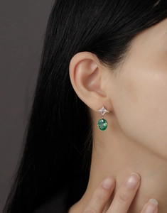Close-up of emerald green oval gemstones on star-cut zircon earrings for women