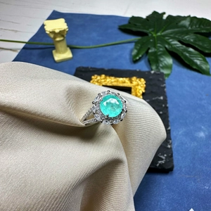 8mm synthetic Paraiba ring in 925 silver with halo diamonds on beige woven fabric