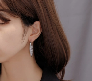 Macro side view of silver hollow hoop earrings with pavé micro-set cubic zirconia on a model