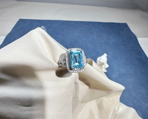 Macro view of emerald-cut aquamarine ring with double halo diamond pave on silver band