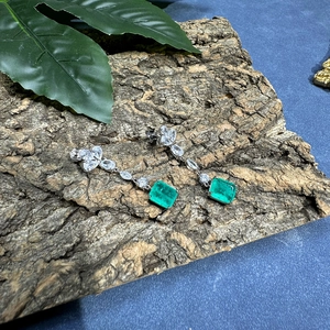 Elegant silver earrings with 8x10mm emerald-cut green gemstones on natural bark