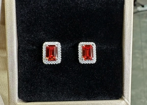 Macro shot of 925 silver stud earrings with emerald cut red ruby and halo diamonds