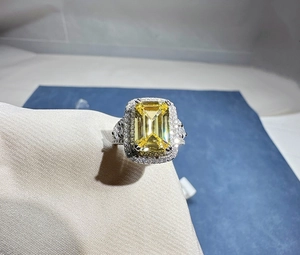 Macro shot of rectangular yellow gem ring with double diamond halo on silver band