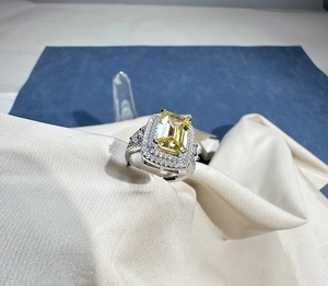 Macro view of 8x12mm emerald-cut yellow gemstone ring with halo diamond setting