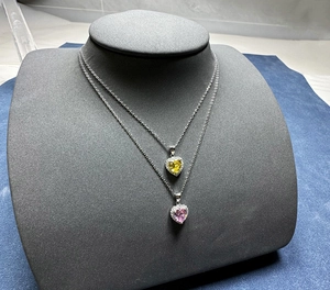 Gros plan de colliers avec cœurs en cristal jaune et rose sur chaînes en argent