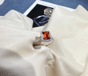 Macro detail of rectangle orange gemstone ring with sparkling pave stones on silver band
