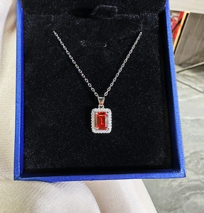 Detail of a rectangular cut ruby pendant with halo diamonds on a silver chain