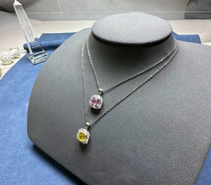 Detailansicht der 925 Silber Halsketten mit rosa und gelben Steinen auf blauem Dekor