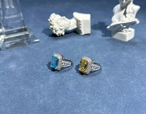 Close-up of emerald-cut aquamarine and yellow gemstone rings with halo diamond accents