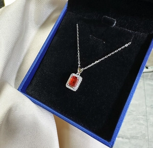 Detailed macro view of an emerald-cut ruby pendant necklace with a halo of small zircons