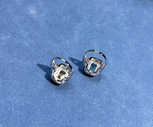 Detail view of two rectangle cut rings with aquamarine and yellow gems in silver bands