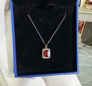 Macro shot of a rectangular ruby pendant with halo diamonds in a blue jewelry box
