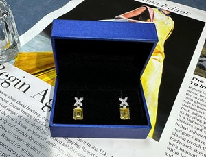 Dettaglio di orecchini a perno con diamante giallo rettangolare in astuccio blu