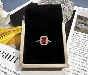 Close-up of emerald cut ruby ring with halo diamonds in a luxury jewelry gift box