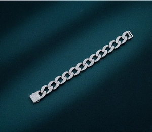 Detailed close-up of a silver-toned iced-out Cuban link bracelet on green silk
