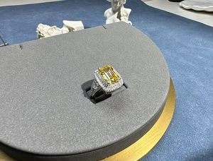 Macro detail of emerald-cut yellow stone ring with sparkling halo setting on a display