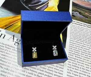 Dettaglio orecchini con diamante giallo e bianco taglio smeraldo in scatola blu