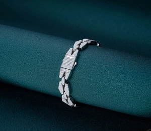 Macro shot of silver iced-out cuban link bracelet with micro-paved diamonds on green prop