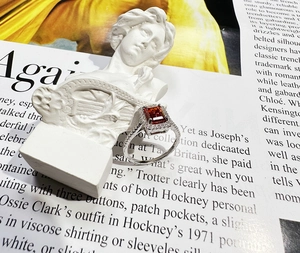 Macro view of emerald-cut ruby ring on a marble base and fashion magazine background