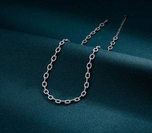 Close-up of silver Cuban link necklace with micro-paved zircons on green fabric
