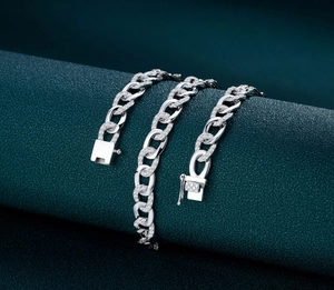 Macro shot of silver cuban link chain with pave zircons on dark green texture stand
